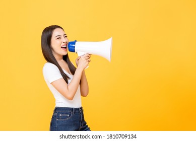 Happy beautiful Asian woman talking on magaphone isolated on yellow background with copy space