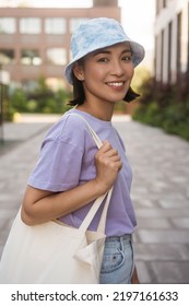 Happy Beautiful Asian Woman Wearing Casual Clothing, Stylish Panama, Holding Shopping Bag  Looking Away On City Street