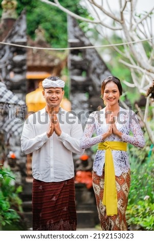 happy beautiful balinese couple greeting and smiling gesture at camera