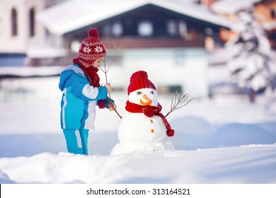 Happy Beautiful Child Building Snowman In Garden, Winter Time