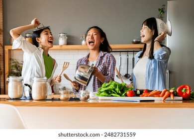 Happy beautiful chinese women friends bonding at home and cooking delicious meal together- Playful pretty asian female adults meeting and having fun at home, concepts about lifestyle, domestic life  - Powered by Shutterstock