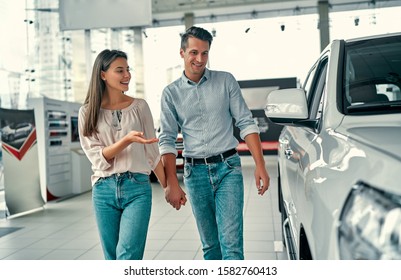 Happy Beautiful Couple Is Choosing A New Car At Dealership.
