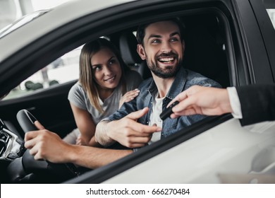 Happy beautiful couple is choosing a new car at dealership. - Shutterstock ID 666270484