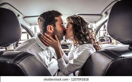 Happy beautiful couple in love kissing in a new car in car dealership.