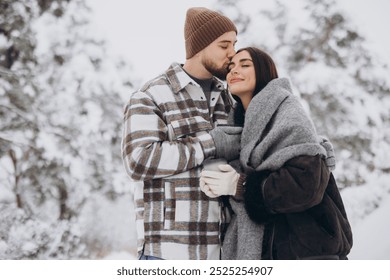 Happy beautiful couple resting and drinking hot tea in the forest in winter in the mountains - Powered by Shutterstock