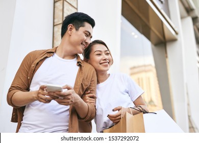 Happy Beautiful Couple Using Smart Phone And Shopping Together.