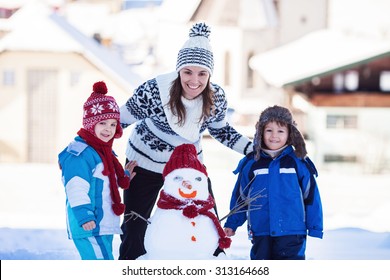 Happy Beautiful Family Building Snowman In Garden, Winter Time, Mom And Two Kids