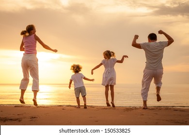 Happy Beautiful Family Dancing On The  Beach On The  Dawn Time.