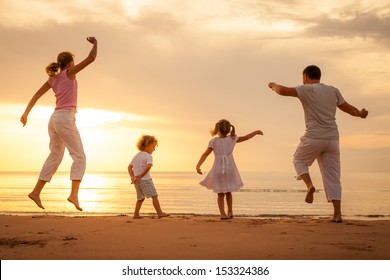 Happy Beautiful Family Dancing On The  Beach On The  Dawn Time.