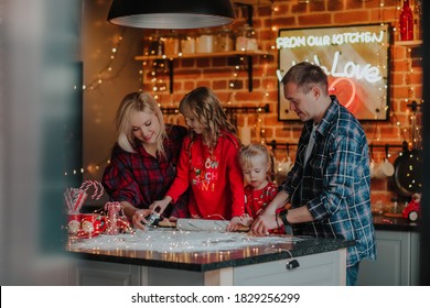 Happy Beautiful Family With A Small Blonde Daughter Roll Out The Dough For Christmas Cookies In The Kitchen, Laughing. 