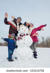 Happy Beautiful Family With Two Kids Near Snowman Outside In Winter Time