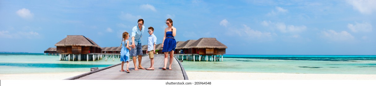 Happy Beautiful Family Walking On Wooden Jetty During Summer Vacation At Luxury Resort Wide Panorama With Copy Space, Perfect For Banners