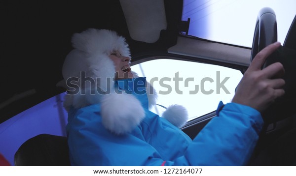 happy and Beautiful girl is dancing and singing\
while driving cars. Woman in car laughs. girl in winter hat turns\
steering wheel of car.