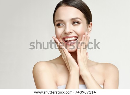 Happy beautiful girl holding her cheeks with a laugh   looking to the side. Pretty woman   clean fresh skin . Expressive facial expressions  .Cosmetology , beauty and Spa
 