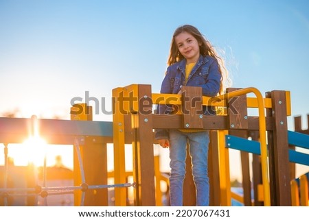 Happy beautiful girl playing on the beach playground against sunset sky
