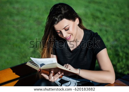 Happy beautiful girl reading a book on sunny spring day on a bench in nature Foto stock © 