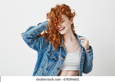 Happy beautiful girl smiling with closed eyes touching her red curly hair over white background. - Shutterstock ID 678396601