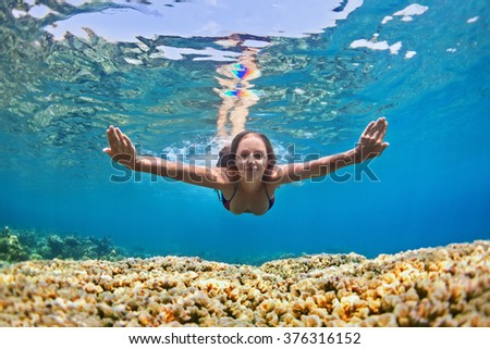 Happy beautiful girl - young woman dive underwater with fun over coral reef in sea pool. Healthy active lifestyle, people water sport outdoor activity and swimming lessons on beach summer holidays.