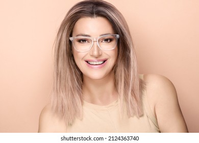 Happy Beautiful Healthy Woman In Clear Glasses Smiling And Looking At Camera Against Beige Background. Clear Vision And Visual Health Concept