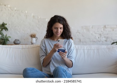 Happy Beautiful Hispanic Customer Woman Holding Credit Card, Using Online Shopping App On Smartphone, Making Payment On Internet Store Website, Paying Bills, Fees, Inserting Data