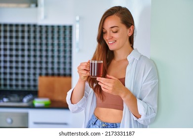 Happy beautiful joyful carefree satisfied attractive woman drinking hot black tea at home kitchen - Powered by Shutterstock