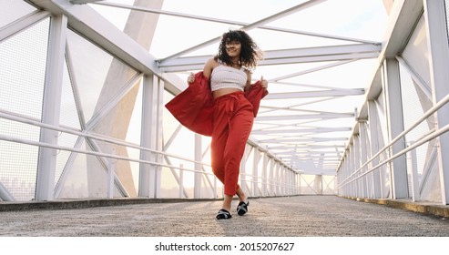 Happy beautiful Latin woman walking and dancing outdoor. Young mixed race carefree girl enjoys the day and dancing in slow motion. Brazilian lady walking on city - Powered by Shutterstock