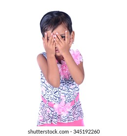 Happy beautiful little girl is playing hide-and-seek hiding face