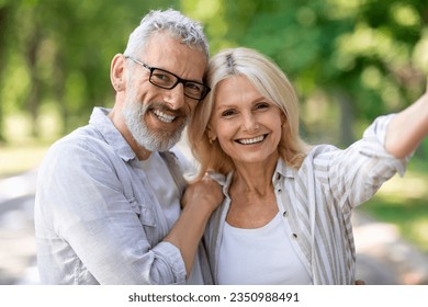 Happy beautiful mature couple posing for selfie together outdoors, cheerful senior man and woman talking photo while walking in park, smiling and looking at camera, enjoying date outside, closeup - Powered by Shutterstock