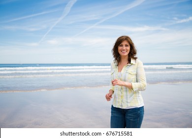 Happy Beautiful Middle Aged Woman Walking Along The Shore On The Beach