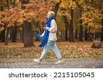 Happy beautiful middle-aged woman walking in autumn park