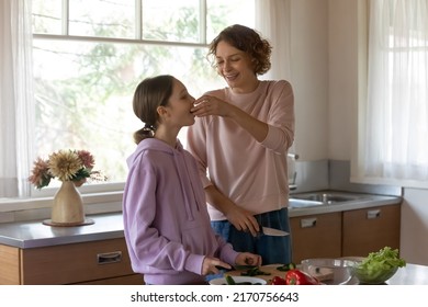 Happy Beautiful Mother And Teenage Daughter Cooking Salad In Modern Kitchen Together, Preparing Dinner, Smiling Mum And Teen Girl Cutting Fresh Vegetables With Knife On Cutting Board