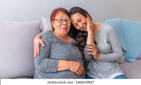 Happy beautiful older Asian mother and adult daughter embracing looking at camera, smiling senior lady hugging young woman, family of different age generations bonding hugging, head shot portrait 