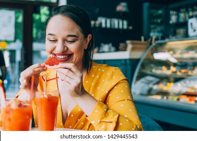 Happy Beautiful Plus Size Woman Laughing And Drinking Healthy Vegan Citrus Fruit Smoothie In City Cafe