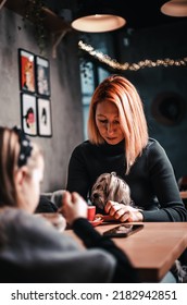 Happy Beautiful Relaxed Mature Older Adult Red-haired Woman Drinking Coffee Relaxing In Coffee Shop. Smiling Stylish Middle Aged 40s Lady Enjoying Coffee With Her Daughter And Dog In Coffee Shop.