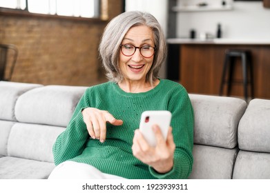 Happy Beautiful Senior Woman Is Using A Smartphone For Video Calling To Family, Friends Or Dating Online. Mature Elderly Lady Holds The Phone And Using App For Video Communication, Online Meeting