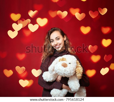 happy beautiful smiling woman with a big toy dog on a red wall background. Valentine's day, mother's day, birthday and a gift