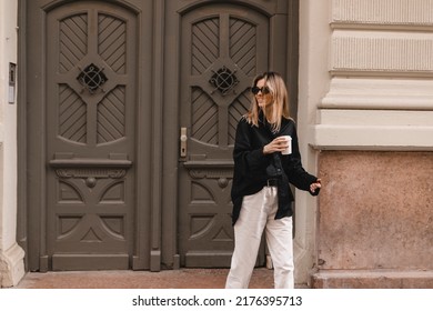 Happy Beautiful Stylish Woman Having Good Fashion Clothes Walking On Street And Holding Some Coffee In Cup Takeaway With Good Mood. Girl Go Away From House And Look At Back, Make Step Hair Fly On Wind