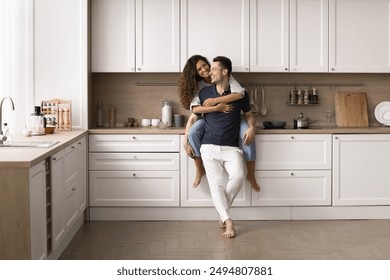 Happy beautiful wife sits on countertop, cuddling husband, smile, enjoy talk, spend time together in good furnished kitchen. New house, bank mortgage for young family, renovation, remodeling services - Powered by Shutterstock