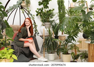 Happy Beautiful Woman With Book In Egg Chair At Home