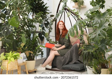 Happy Beautiful Woman With Book In Egg Chair At Home