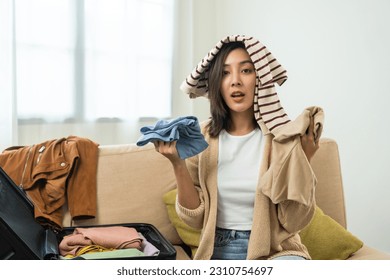 Happy Beautiful woman to folding her clothes pack suitcase for travel in holiday. Young female folding clothes while packing luggage at home. - Shutterstock ID 2310754697