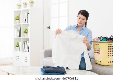 Happy Beautiful Woman Holding White Shirt Checking Dirty Stain Clearing And Ready To Folding In Living Room With Many Messy Family Clothing.