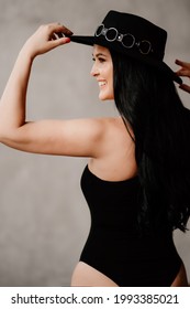 Happy And Beautiful Woman With Long Dark Hair In A Black Bodysuit And Hat. Country Style. Sexy Underwear And Clothes For The Theme Party.