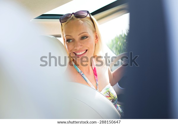 Happy\
beautiful woman looking back while driving\
car