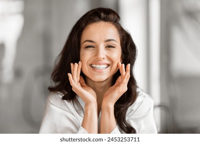 A happy beautiful woman is pampering her skin in the bathroom focusing on skin care routine and beauty - Powered by Shutterstock