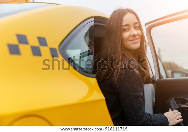 Happy beautiful woman\
sits in yellow taxi