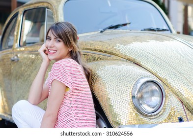 Happy Beautiful Woman Sitting Against Gold Retro Car. 