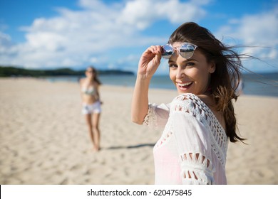 Happy beautiful woman standing on beach with friend laughing