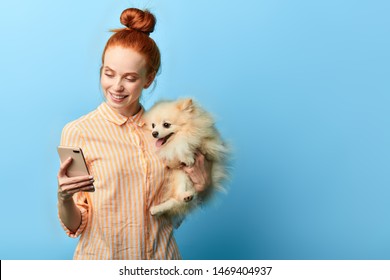Happy Beautiful Woman In Striped Stylish Shirt Buying Clothes Online For Her Pet. Girl Has Found Good Vet Clinic For The Dog. Close Up Portrait, Isolated Blue Background, Copy Space