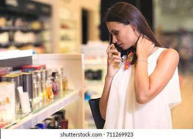 Happy Beautiful Woman Testing Perfumes In Cosmetics Store